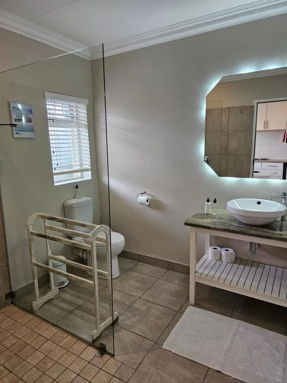 Bathroom with a vessel basin, backlit mirror and glass shower screen