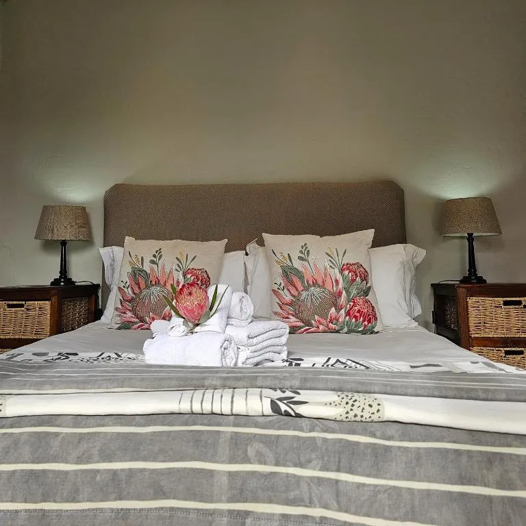 Bed dressed with protea-print cushions and rolled towels for arrival