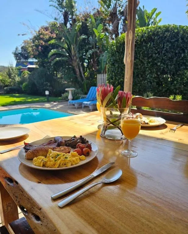 Cooked breakfast plated on a wooden table beside the pool and garden