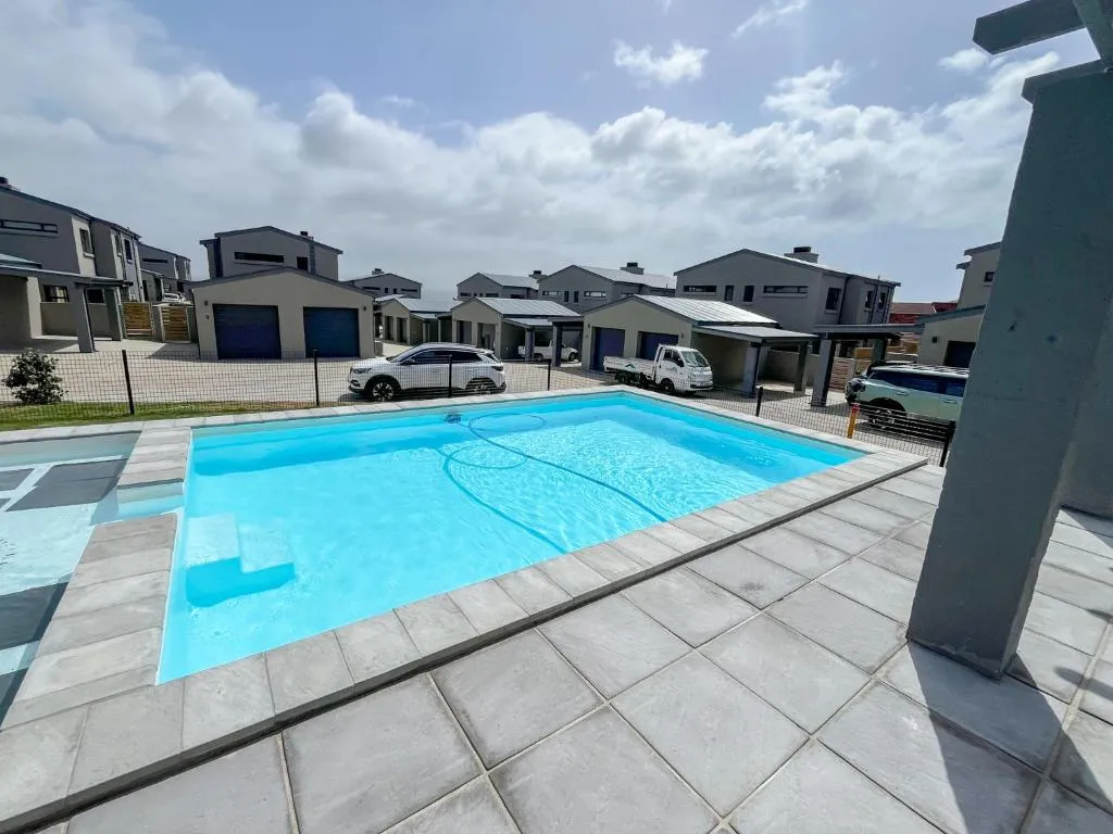 Communal estate pool shared with neighbouring townhouses, parking and garages beyond the fence