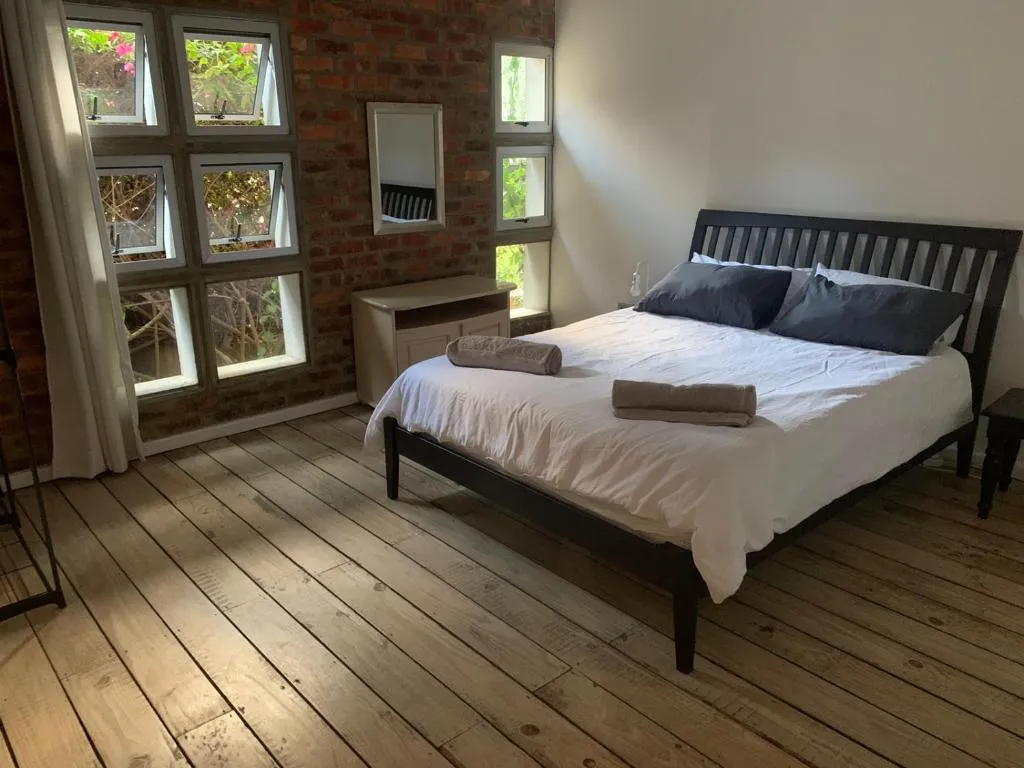 Bedroom with dark wood bed frame and tall windows looking onto flowering garden