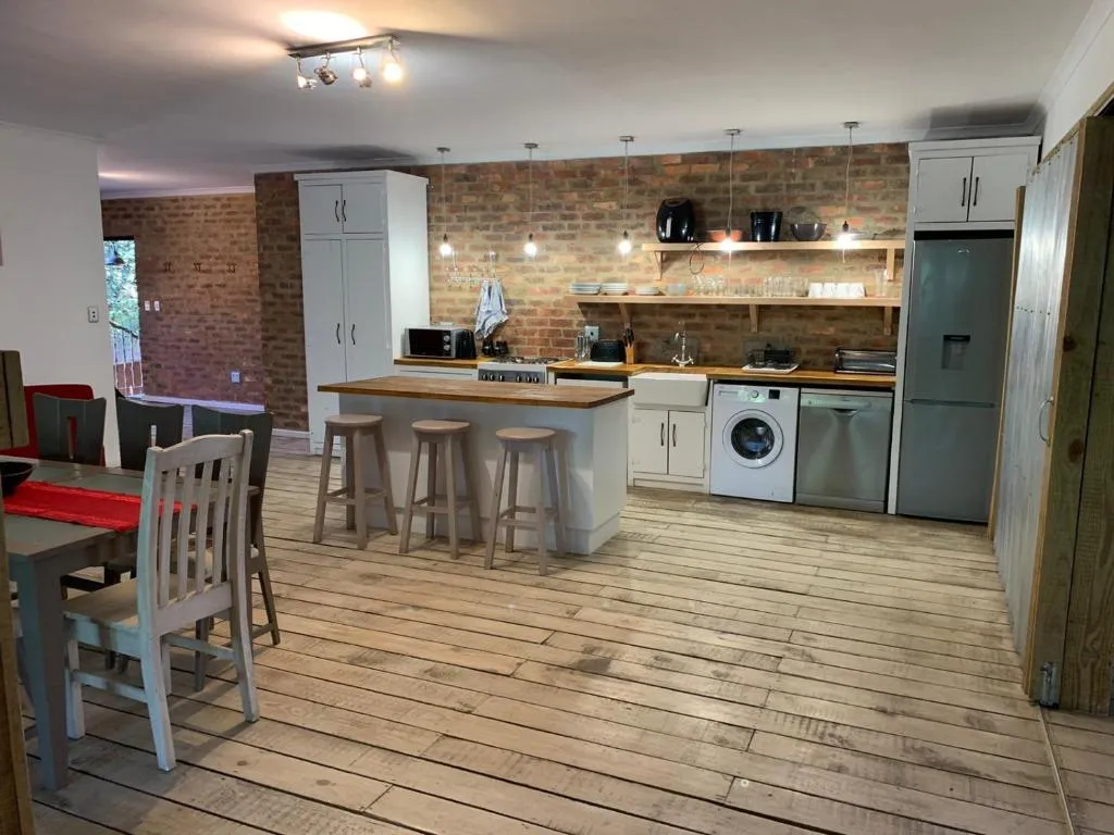 Open-plan kitchen and dining area with an island, bar stools and exposed brick wall