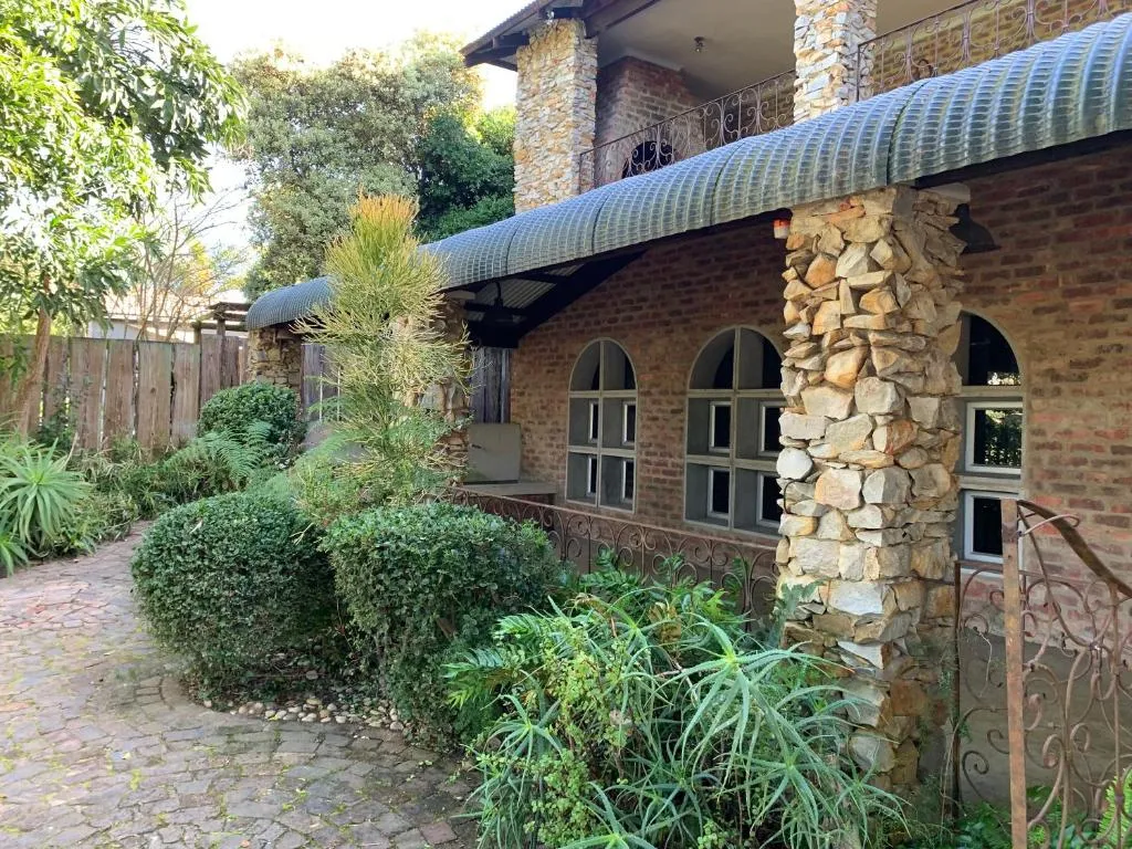 Stone and brick cottage exterior with arched windows and a lush garden path
