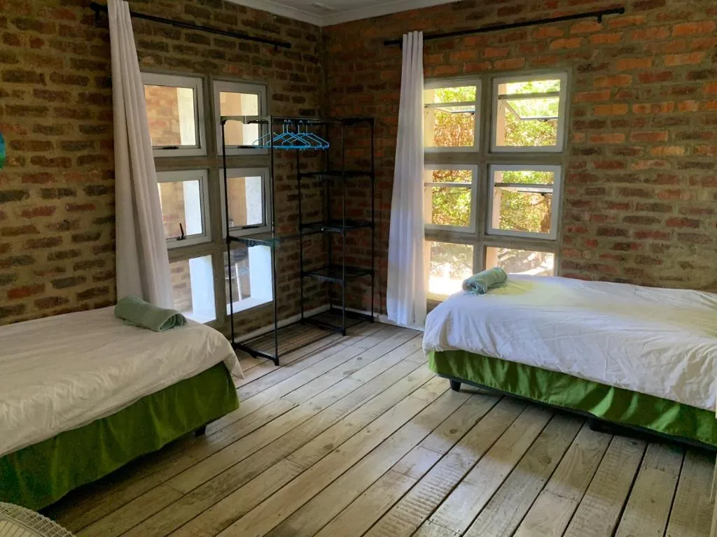 Twin bedroom with exposed brick walls and windows onto the garden
