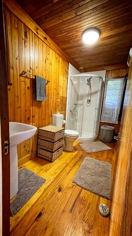 Pine-panelled bathroom with pedestal basin, shower cubicle and toilet