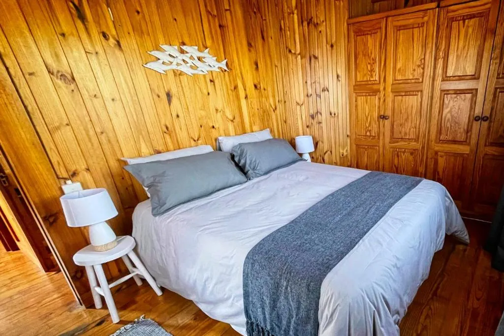 Pine-panelled bedroom with wood headboard, bedside lamps and built-in wardrobes