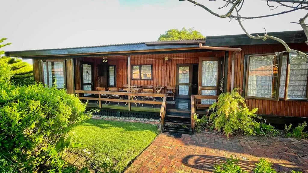 Timber-clad chalet exterior with a full-length covered porch and garden path