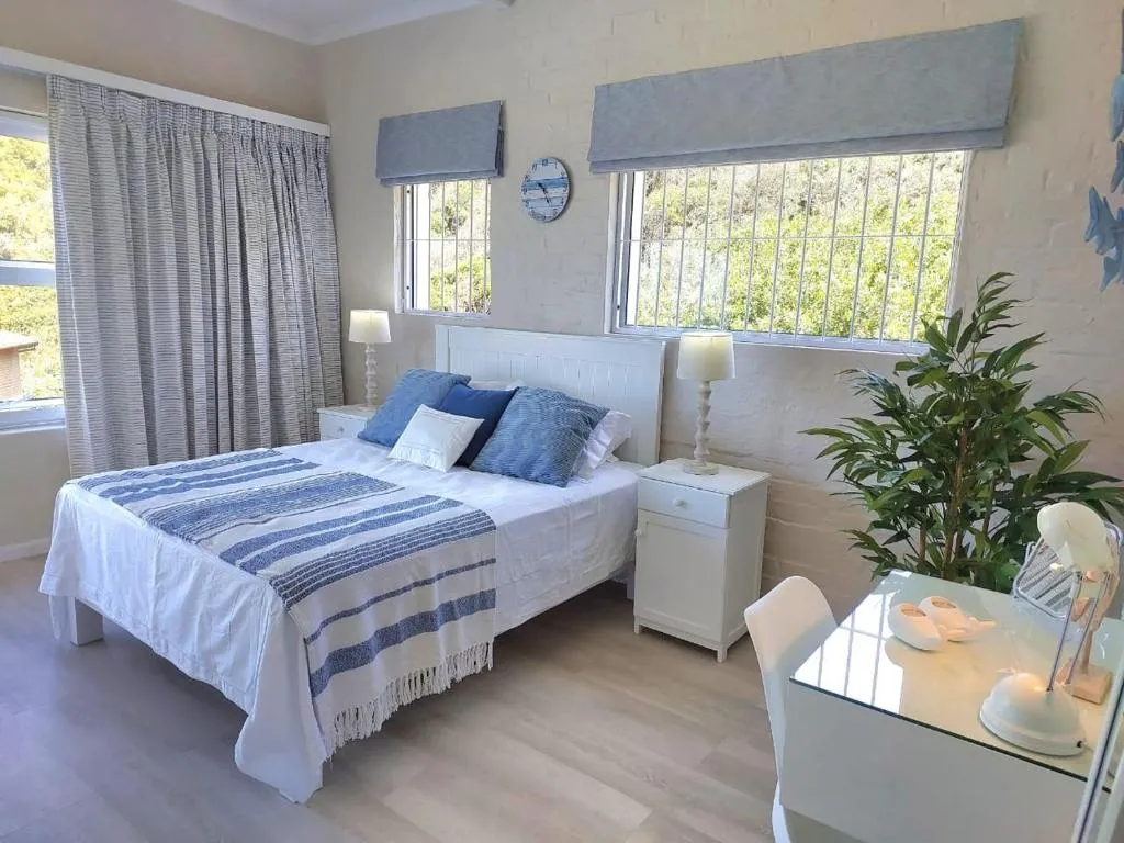 Blue and white bedroom with a queen bed, barred windows, and a garden outlook