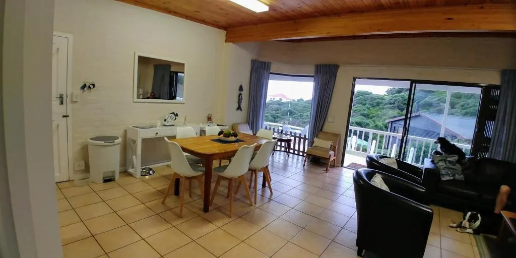 Open-plan dining and lounge area with a wooden ceiling and sliding doors to the balcony