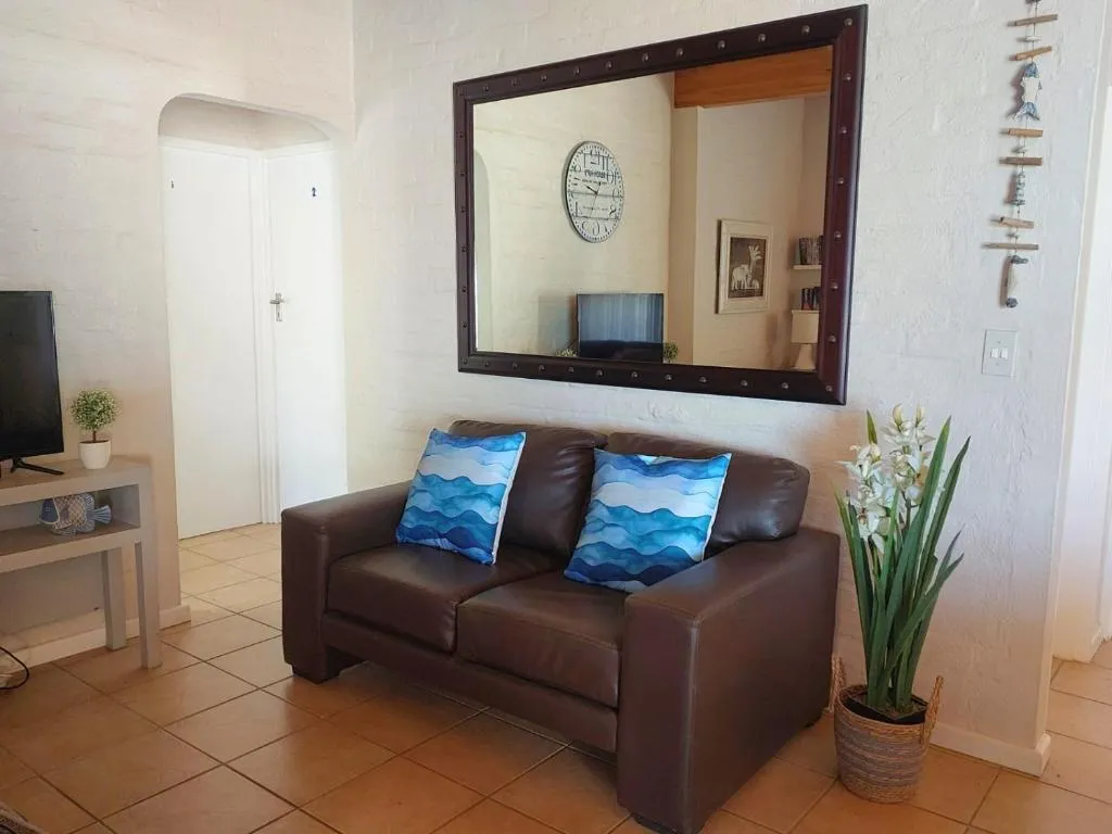 Lounge with a brown leather couch, wall mirror, and mounted television