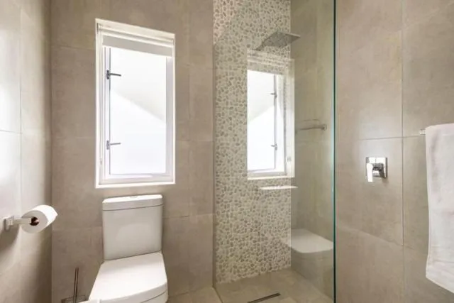 Bathroom with diamond mosaic shower tiling, a window and toilet