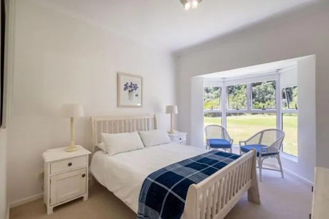 Bedroom bay window with two armchairs looking onto a lawned garden