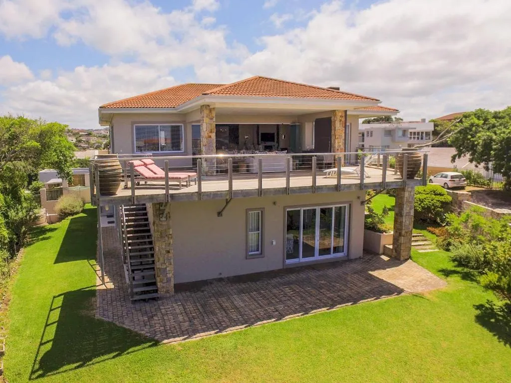 Aerial view of a double-storey villa with terracotta roof, wraparound balcony, and manicured back garden