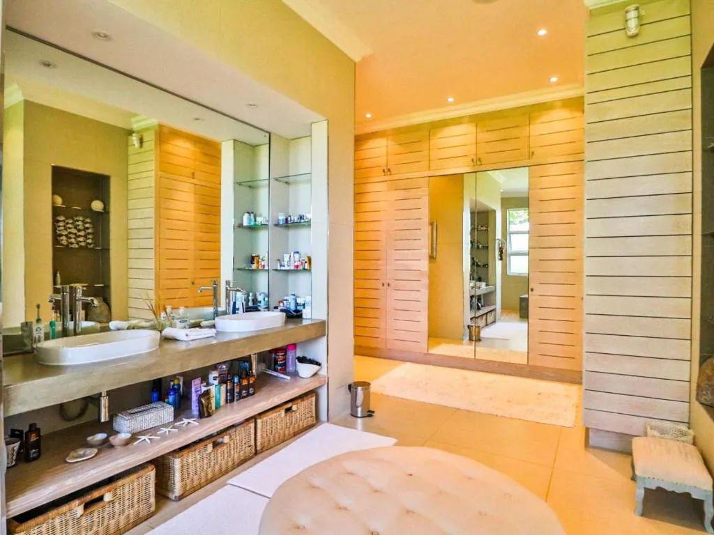 En-suite bathroom with double vanity, walk-in mirrored wardrobe and a freestanding stool
