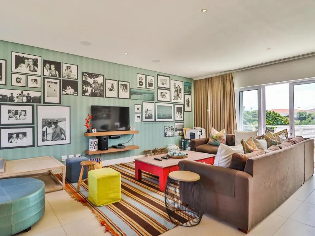 Living room with a sectional sofa, mounted TV and a wall of framed family photographs
