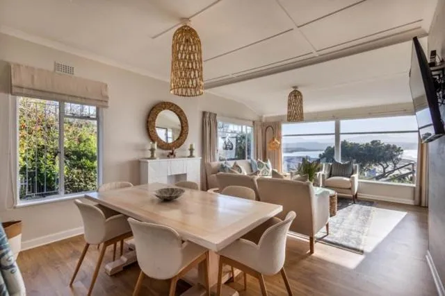 Open-plan dining and living room with table seating six and sea view through windows