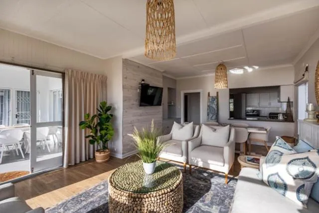 Living room with woven pendant lights, armchairs and kitchen visible beyond