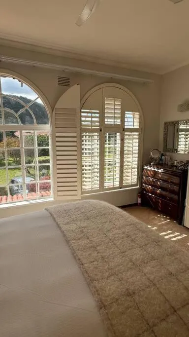 Bedroom with an arched shuttered window overlooking a garden and hillside