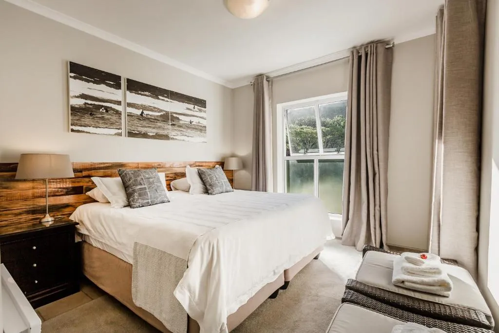 Bedroom with a wood headboard, surf photography triptych and garden-facing window