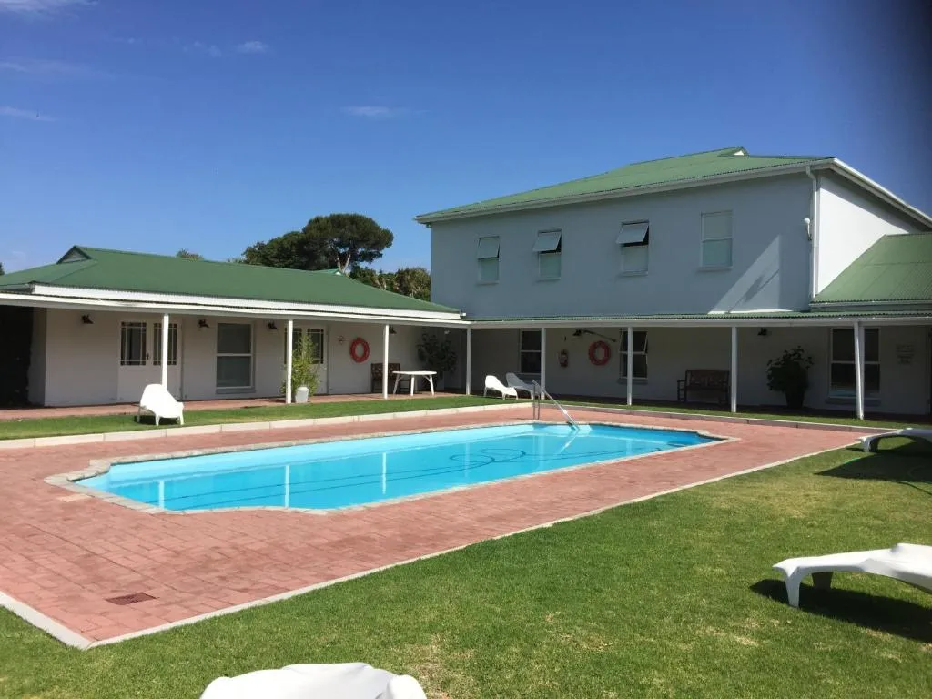 Communal rectangular pool and terrace behind a row of green-roofed veranda units