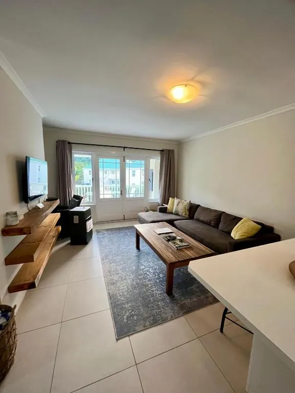 Second lounge with a sectional sofa, floating TV shelf and sliding balcony door