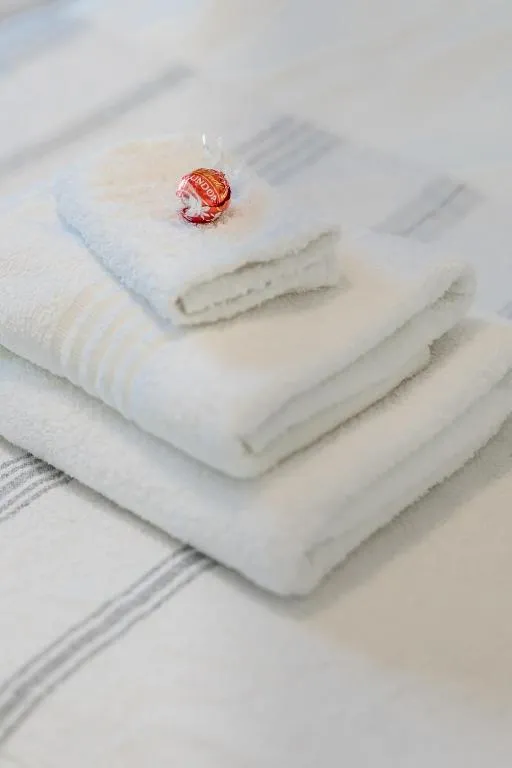 Folded welcome towels with a wrapped chocolate on the bed linen