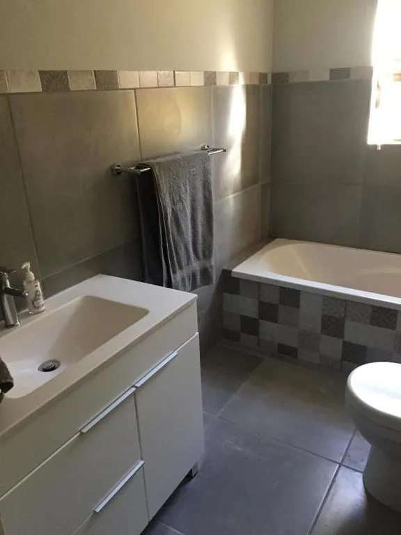 Bathroom with a tiled bath, wall-mounted vanity and a separate toilet