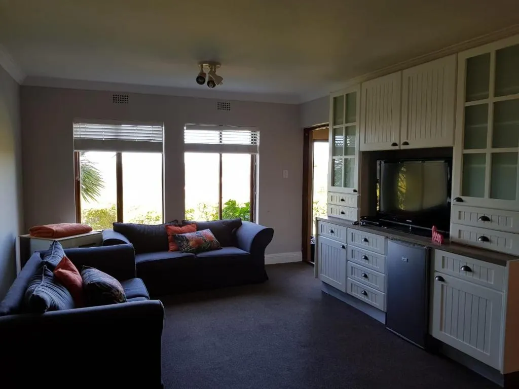Living room with blue sofas and a built-in display cabinet beside the kitchenette