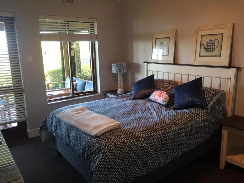 Main bedroom with patterned bedding, artwork above the headboard and a garden-facing window