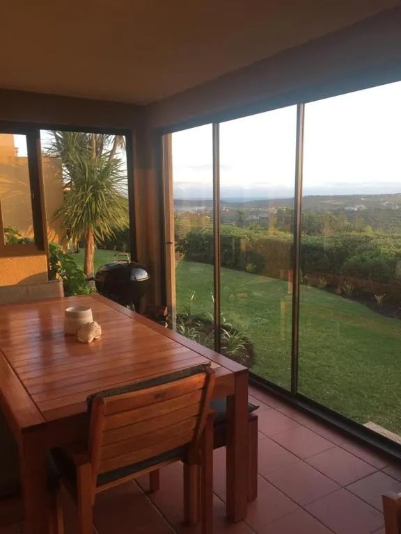 Covered patio dining table with floor-to-ceiling windows overlooking hills and farmland