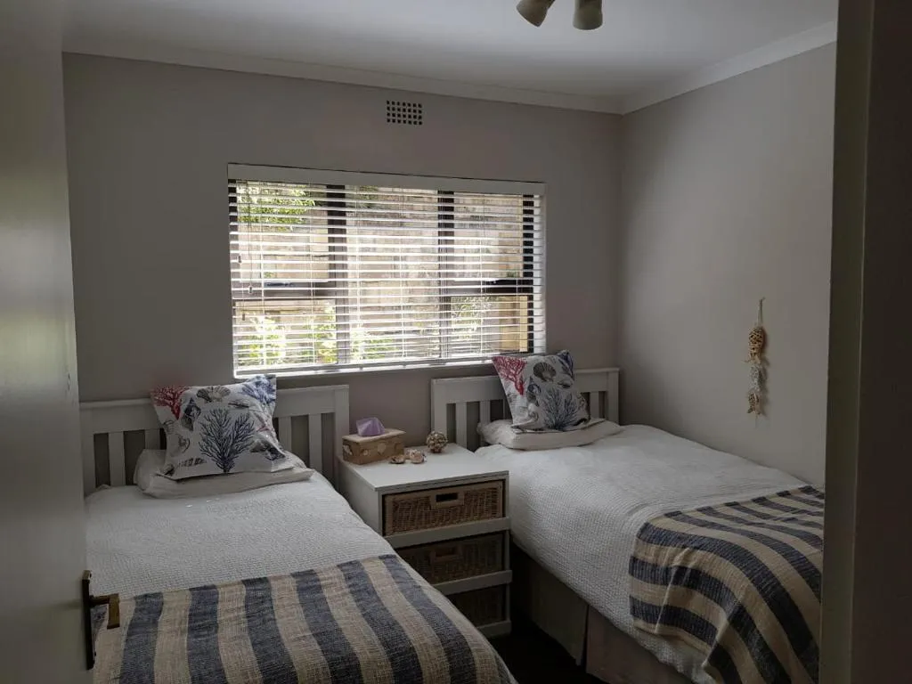 Twin bedroom with matching beds, striped throws and a shared bedside cabinet