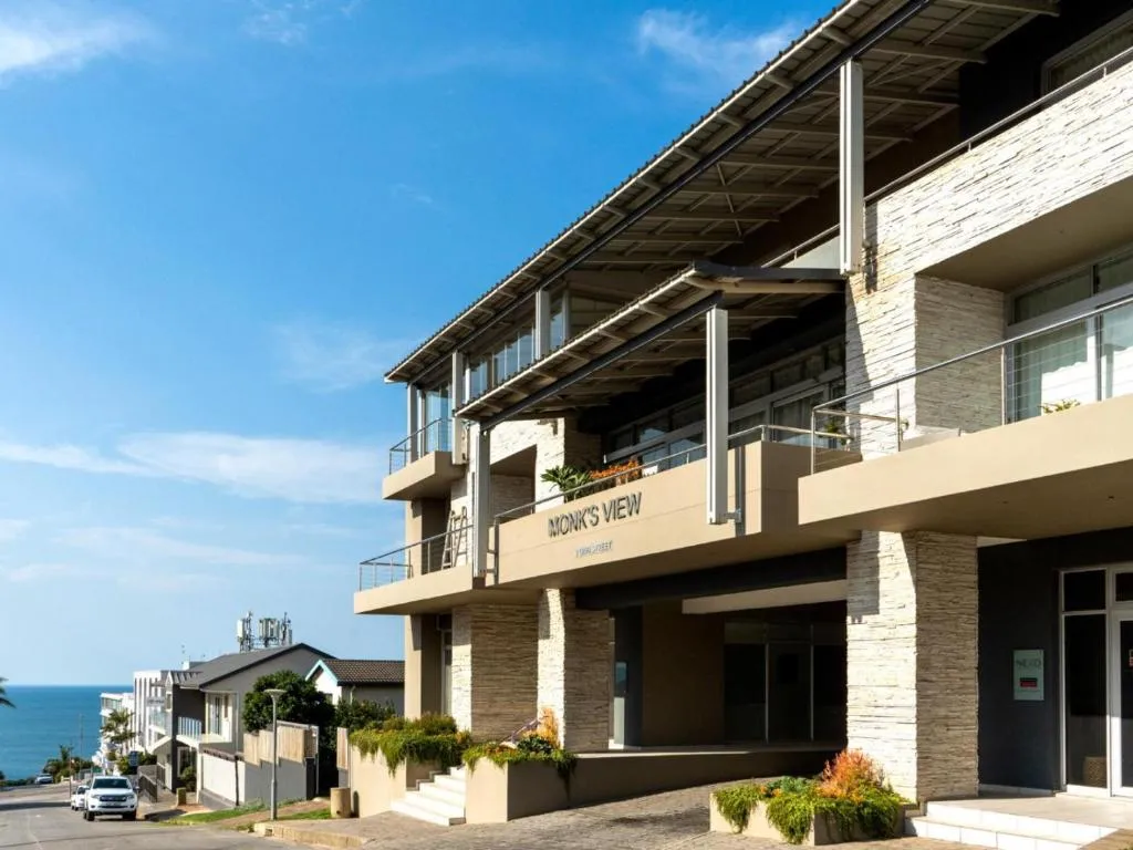 Monk's View building entrance with stacked-stone cladding, balconies and street parking
