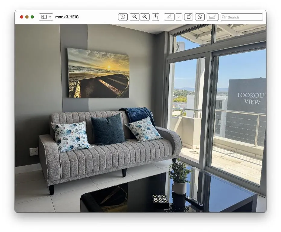 Living room with a grey sofa and sliding glass door onto a balcony within the complex