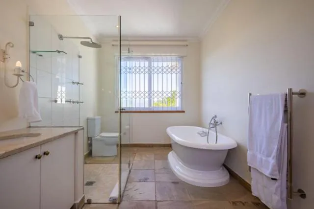 Bathroom with a freestanding tub, glass shower enclosure and a garden-facing window
