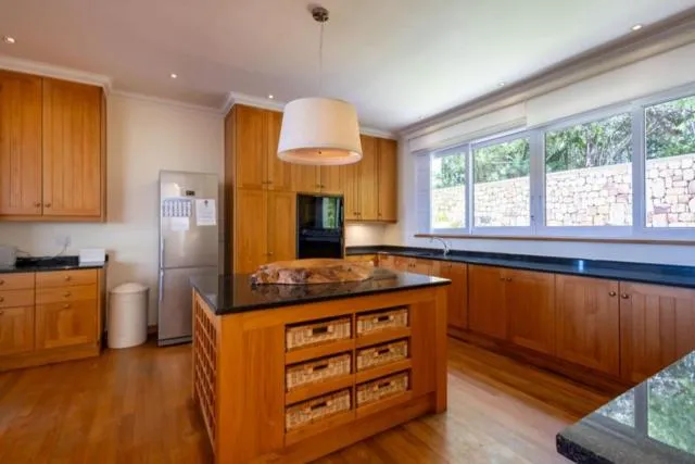 Wood-cabinet kitchen with a black-topped island, basket drawers and a stone garden wall view