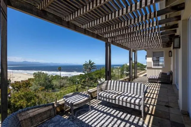 Shaded terrace with wicker seating looking down over the beach, dunes and the ocean horizon
