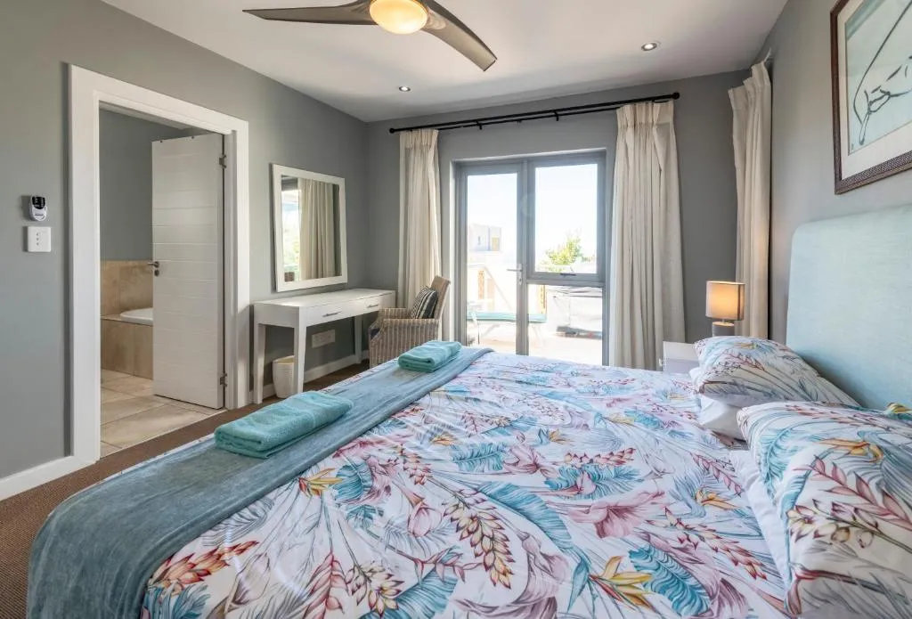 Bedroom with an en-suite bathtub visible through the open door and balcony doors onto a terrace
