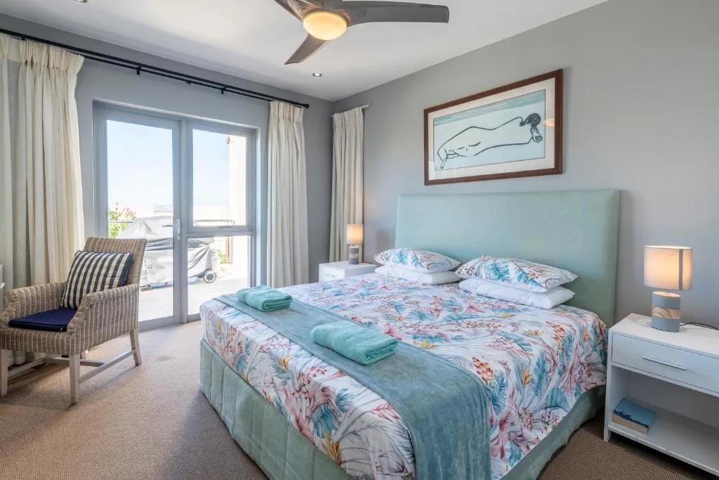 Bedroom with duck-egg headboard, floral linen and glass doors leading onto a private balcony