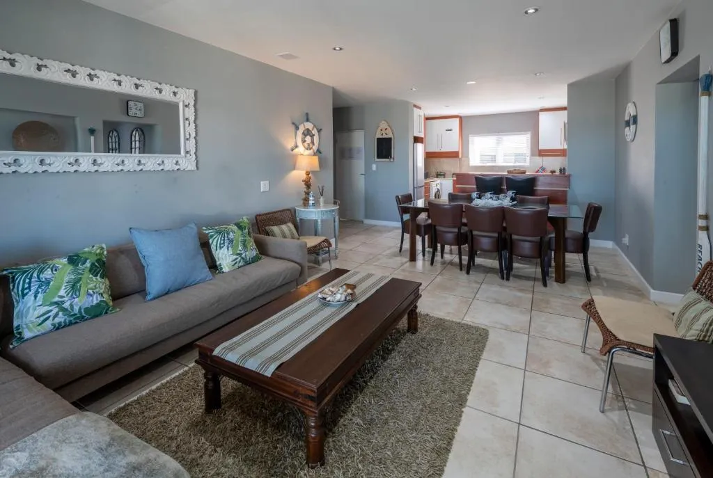 Open-plan lounge and dining room with nautical decor, seating for eight and a view through to the kitchen