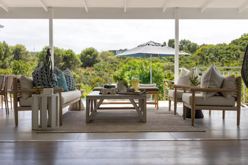 Outdoor lounge seating under a covered patio roof with a market umbrella beyond