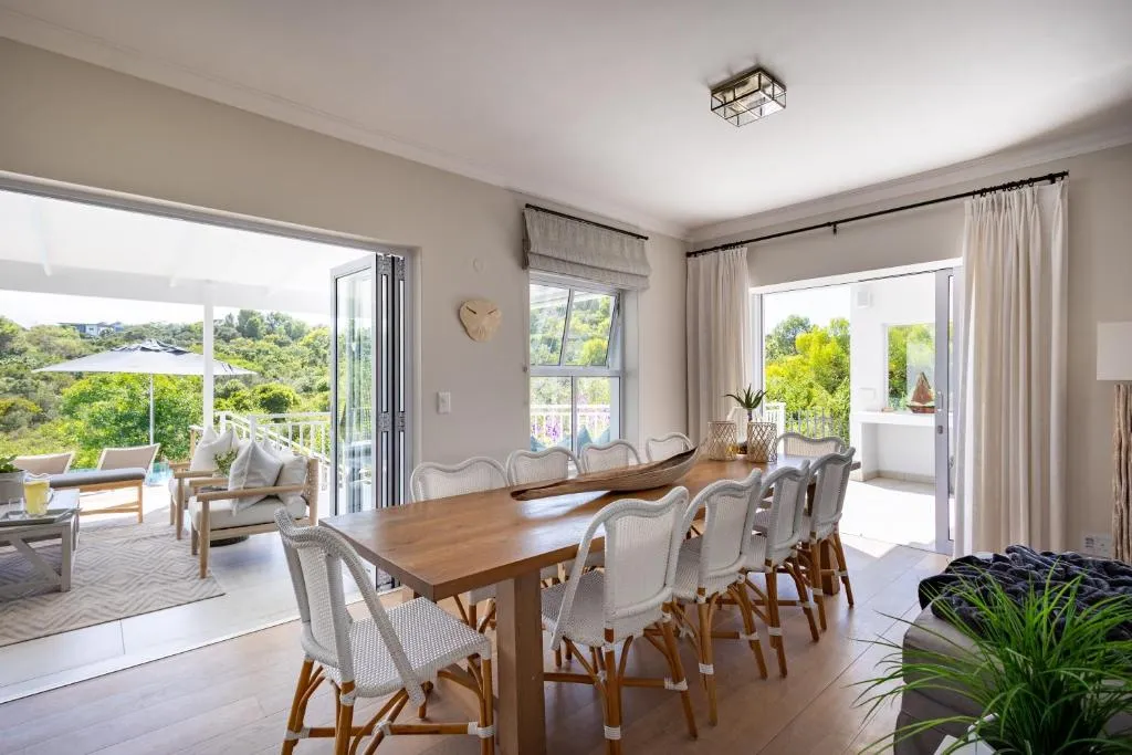 Dining room with a long wooden table seating twelve, opening onto the patio