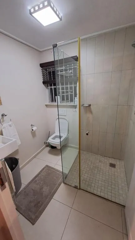 En-suite shower room with a frameless glass enclosure, toilet and floor mat