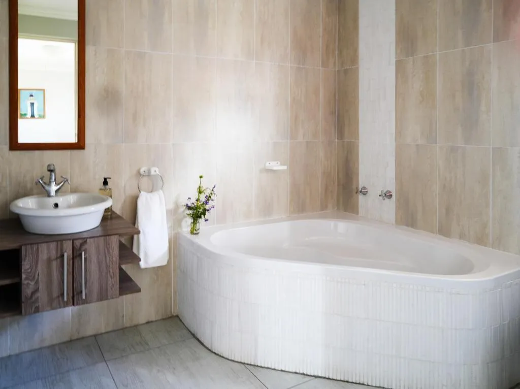 Bathroom with a corner soaking tub, pedestal basin and timber-topped vanity