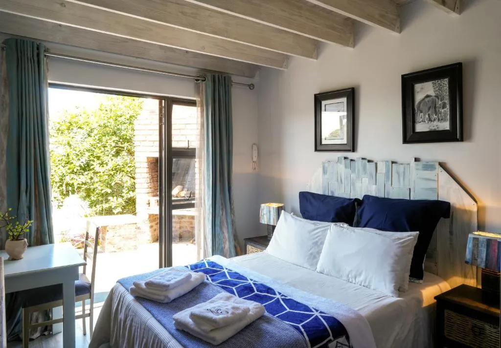 Bedroom with beamed ceiling and sliding doors open to a brick braai and patio