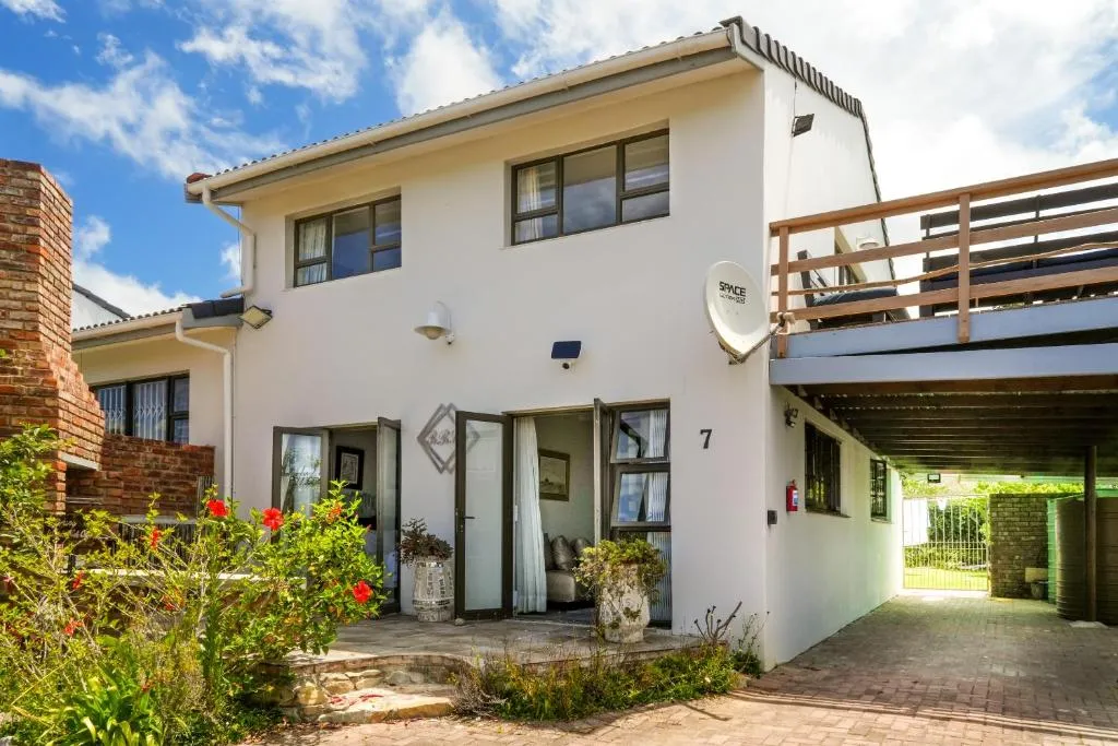 Double-storey house exterior with a covered balcony, carport and flowering entrance garden