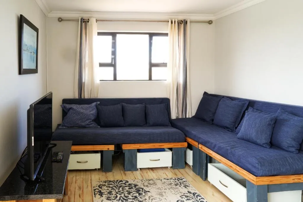 Living room with a dark blue L-shaped sofa and TV stand below a bright window