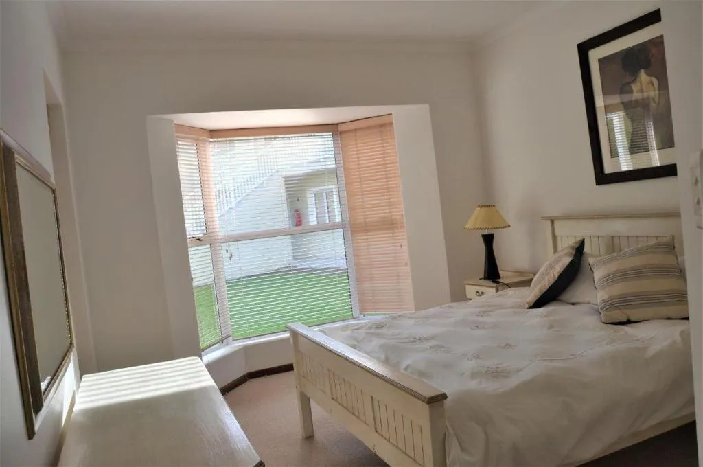 Bedroom with a bay window overlooking a communal lawn and neighbouring units