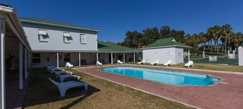 Communal pool at Riverclub with loungers, palm trees and a tennis court alongside