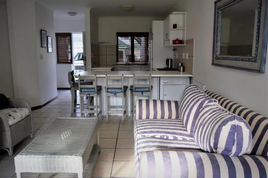 Open-plan lounge with a striped sofa and a breakfast bar leading through to the kitchen