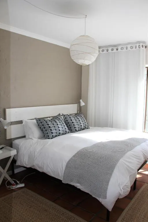Bedroom with a white bed, taupe accent wall, and a paper pendant light